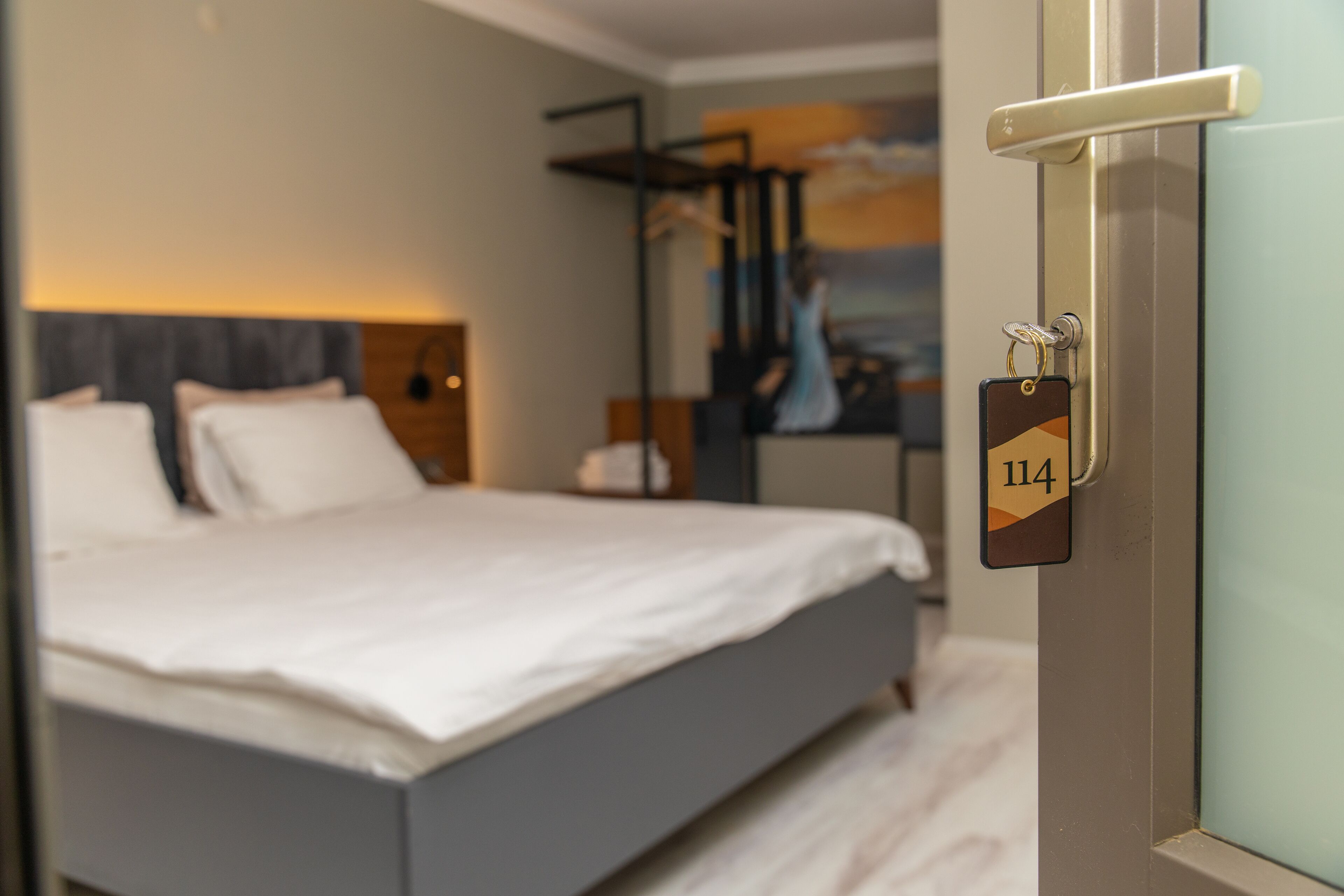Una habitación de hotel moderna con una cama, una mesita de noche y un cuadro en la pared.