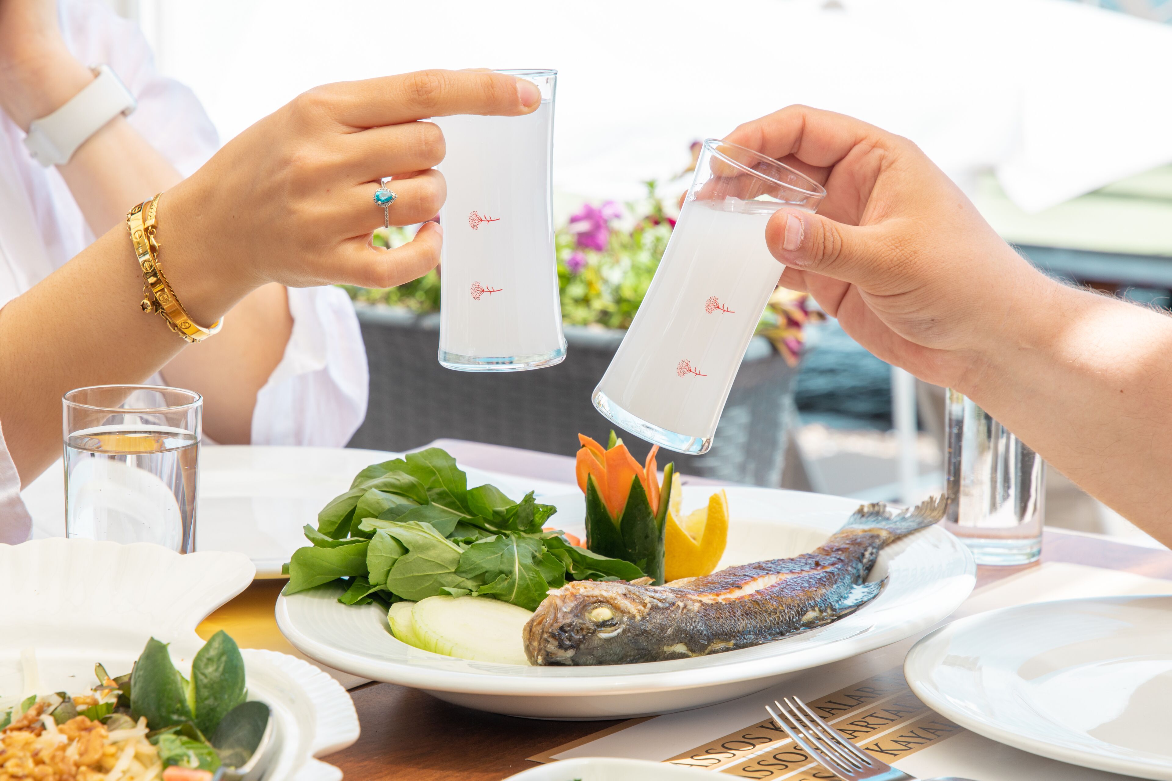A dining table with plates of food, including fish and vegetables, and two glasses of water.