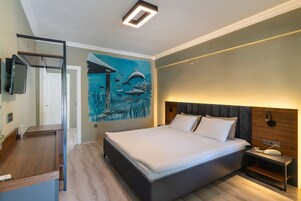 A modern bedroom with a large bed, a nightstand, a wall-mounted TV, and a mural of dolphins.