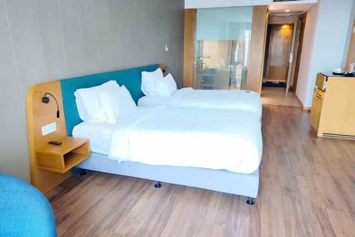 A hotel room with a bed, a desk, and a view of the hallway.