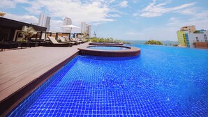 A rooftop pool with lounge chairs and a hot tub, surrounded by buildings and a clear sky. - Quinter Central Nha Trang (Nha Trang)