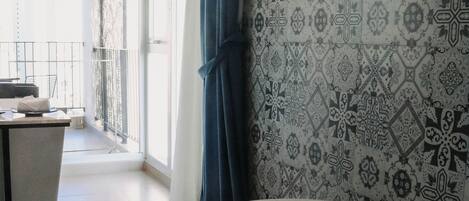 Un baño moderno con una bañera independiente, papel tapiz estampado y vistas a un balcón con barandilla.