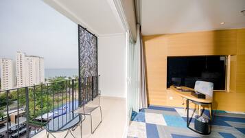 A balcony with a view of the sea, a desk with a chair, and a patterned screen.