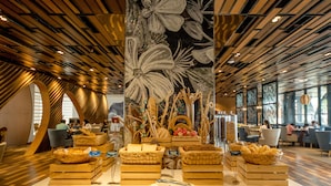 A buffet setup with wooden crates and baskets containing bread and other items, set in a modern interior with a patterned ceiling and large windows. - Quinter Central Nha Trang (Nha Trang)