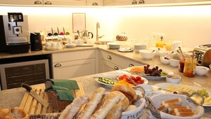 Una cocina bien equipada con cafetera, diversos productos para el desayuno y tabla de cortar con pan.