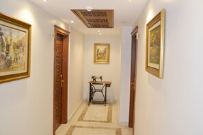 A hallway with wooden doors, a sewing machine on a table, and framed artwork on the walls.