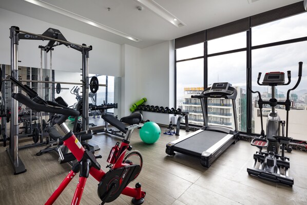 A gym with cardio equipment, weight machines, and a green exercise ball.