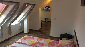 Une chambre avec un lit, une télévision et une fenêtre avec des rideaux.