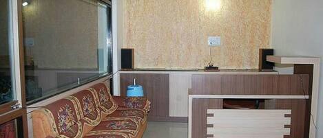 Un espace d’accueil avec un canapé, un bureau en bois et un mur orné d’un motif.