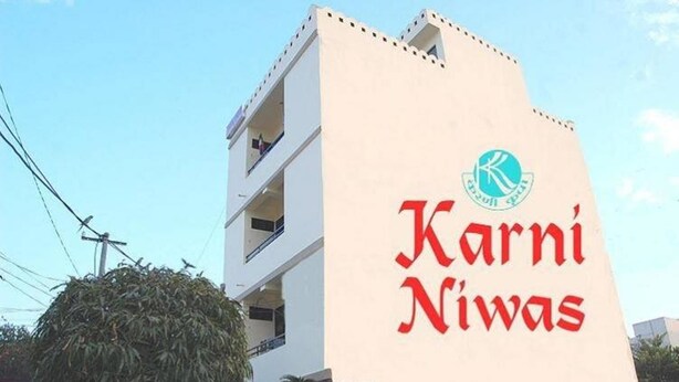 Un edifici amb un rètol que diu "Karni Niwas" i un logotip a sobre del text.