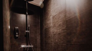 Una ducha moderna con cabezal de ducha de mano y grifo empotrado en la pared.