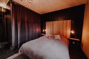 A modern bedroom with a large bed, dark curtains, a wooden headboard, and two bedside lamps. - At Home (Gesves)