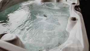 Un jacuzzi con agua, una perilla de control y un tapón de drenaje.