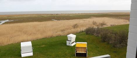 A balcony with a view of a grassy field and a body of water.