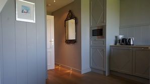 A kitchen with wooden cabinets, a microwave, and a coffee maker. - Ferienwohnung Feskerdam 28 OG (Sylt)