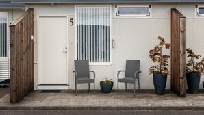 A building with a white door marked with the number 5, two grey chairs, and two potted plants. - South Central Apartments (Selfoss)
