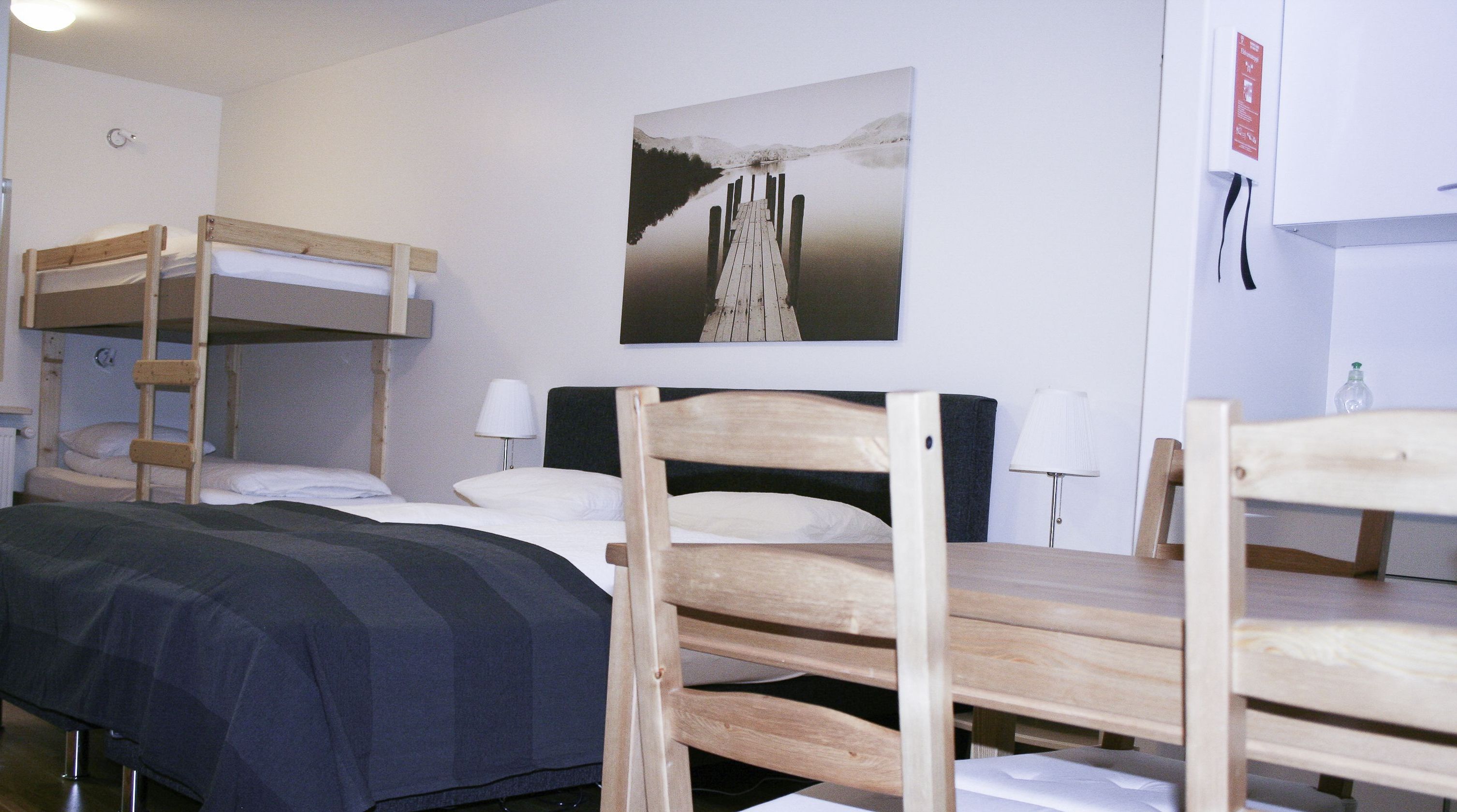 Una camera del dormitorio con letti a castello, una scrivania, una sedia, una lampada e un quadro raffigurante un lago.