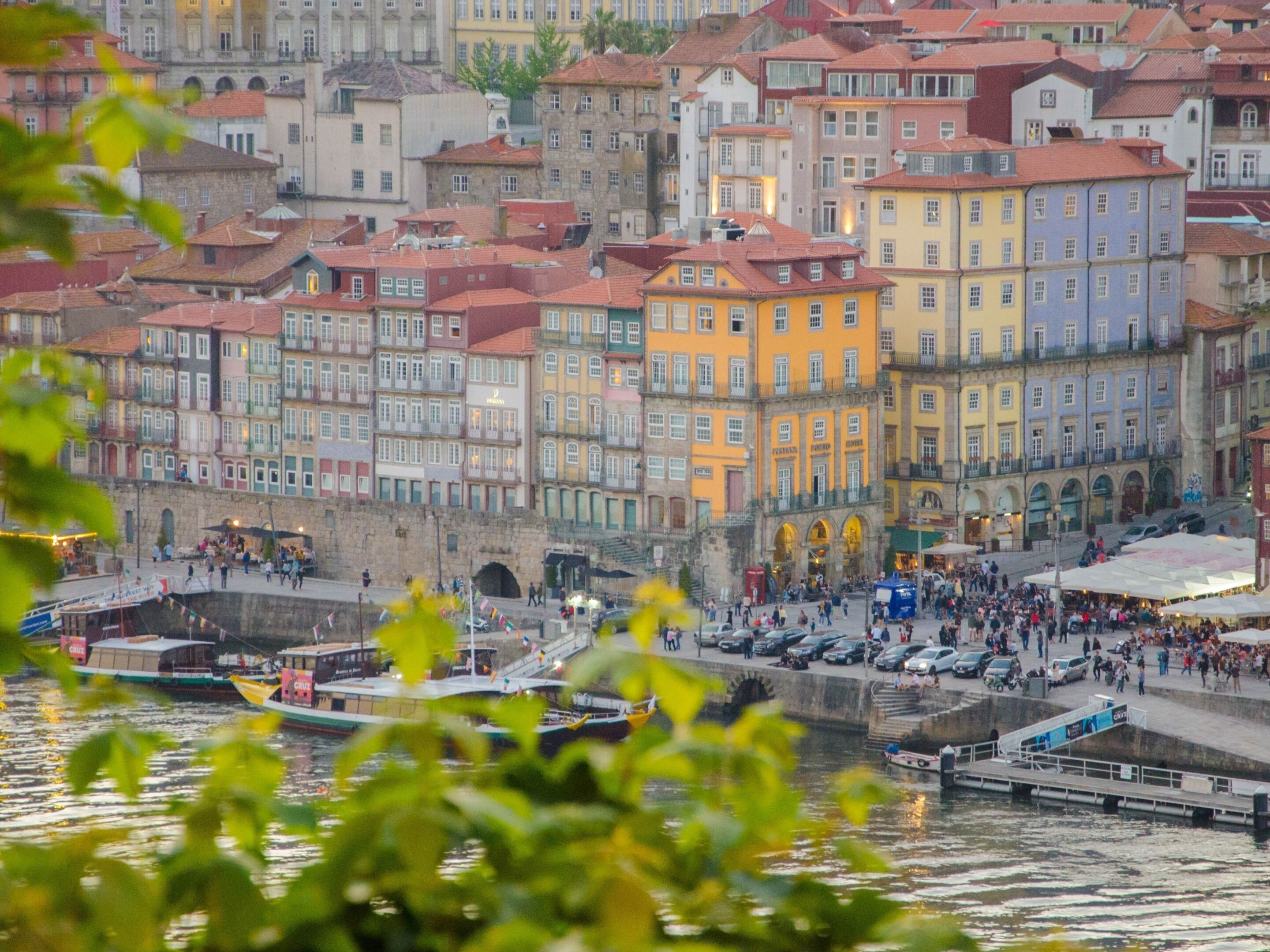 A waterfront area with colorful buildings, a dock with boats, and a stone bridge.