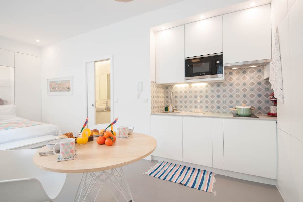 A modern, compact kitchen with white cabinetry, a Bosch microwave, and a small countertop.