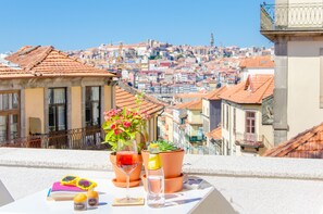 A terrace with a table set for two, featuring a wine glass, a bottle, and a book. - Porto Moments Apartments (Vila Nova de Gaia)