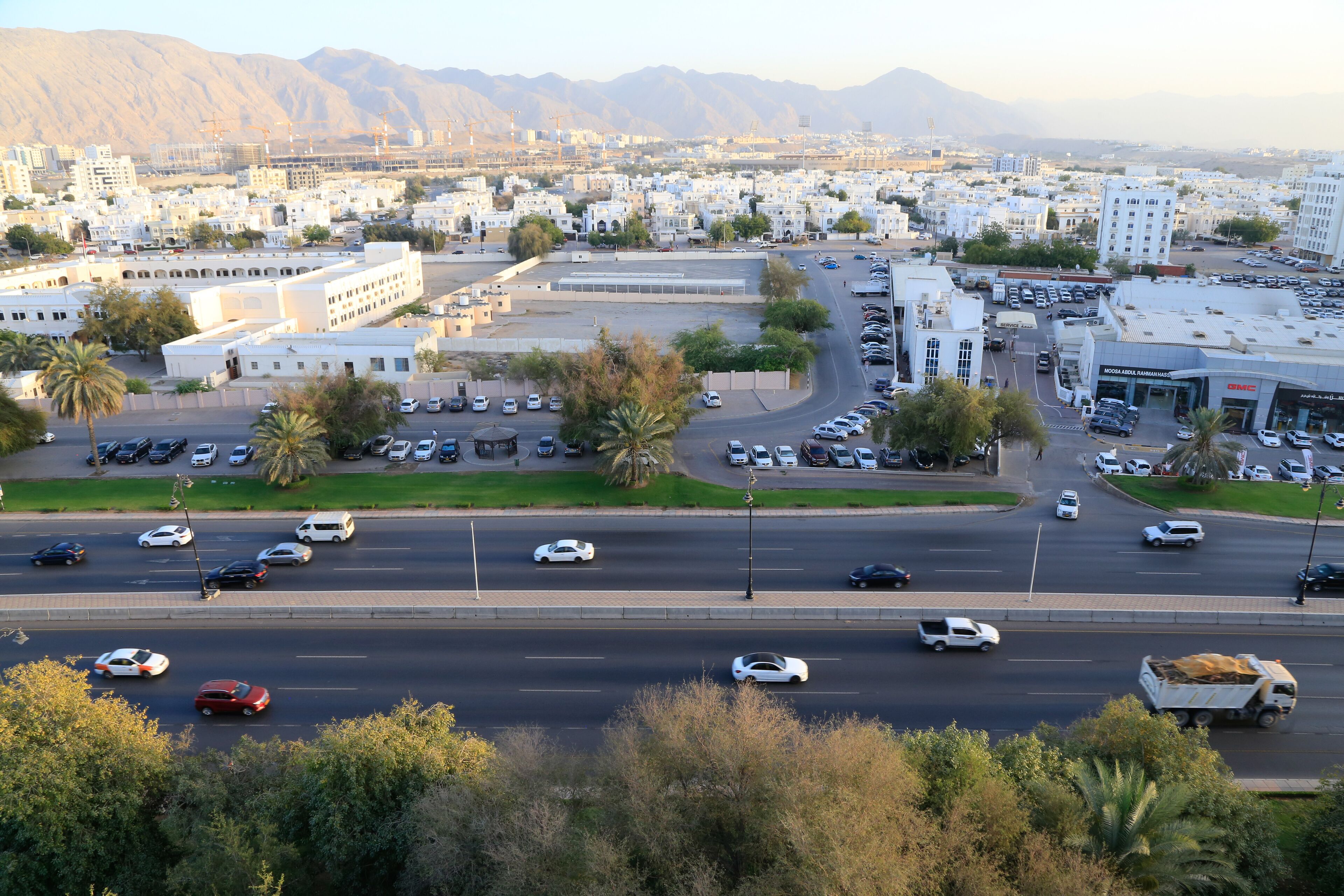A cityscape with a wide road, buildings, and mountains in the background.
