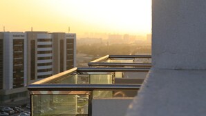 Un edificio de gran altura con varios balcones y un paisaje urbano al fondo.