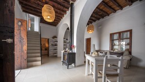 A spacious living area with a staircase, a dining table with chairs, a sofa, and a fireplace. - Agroturismo Can Cosmi Prats (Santa Eulalia del Rio)