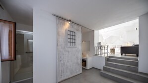 A modern interior with a sliding door leading to a bathroom, a staircase, and a living area with a sofa and a coffee table. - Agroturismo Can Cosmi Prats (Santa Eulalia del Rio)