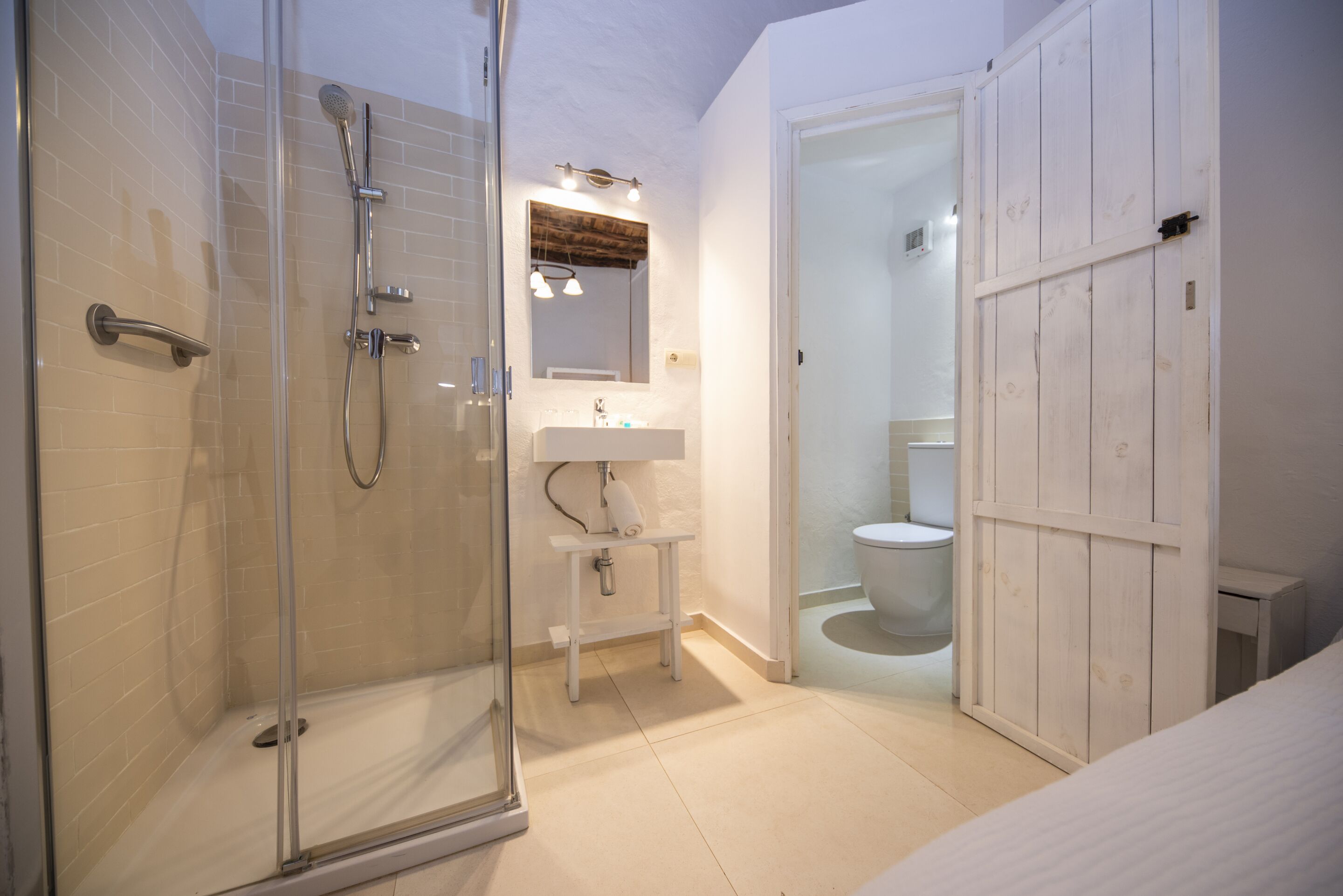 A bathroom with a glass-enclosed shower, a sink, a mirror, and a toilet.