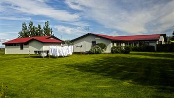 A large, single-story building with a red roof, surrounded by a well-maintained lawn and trees.