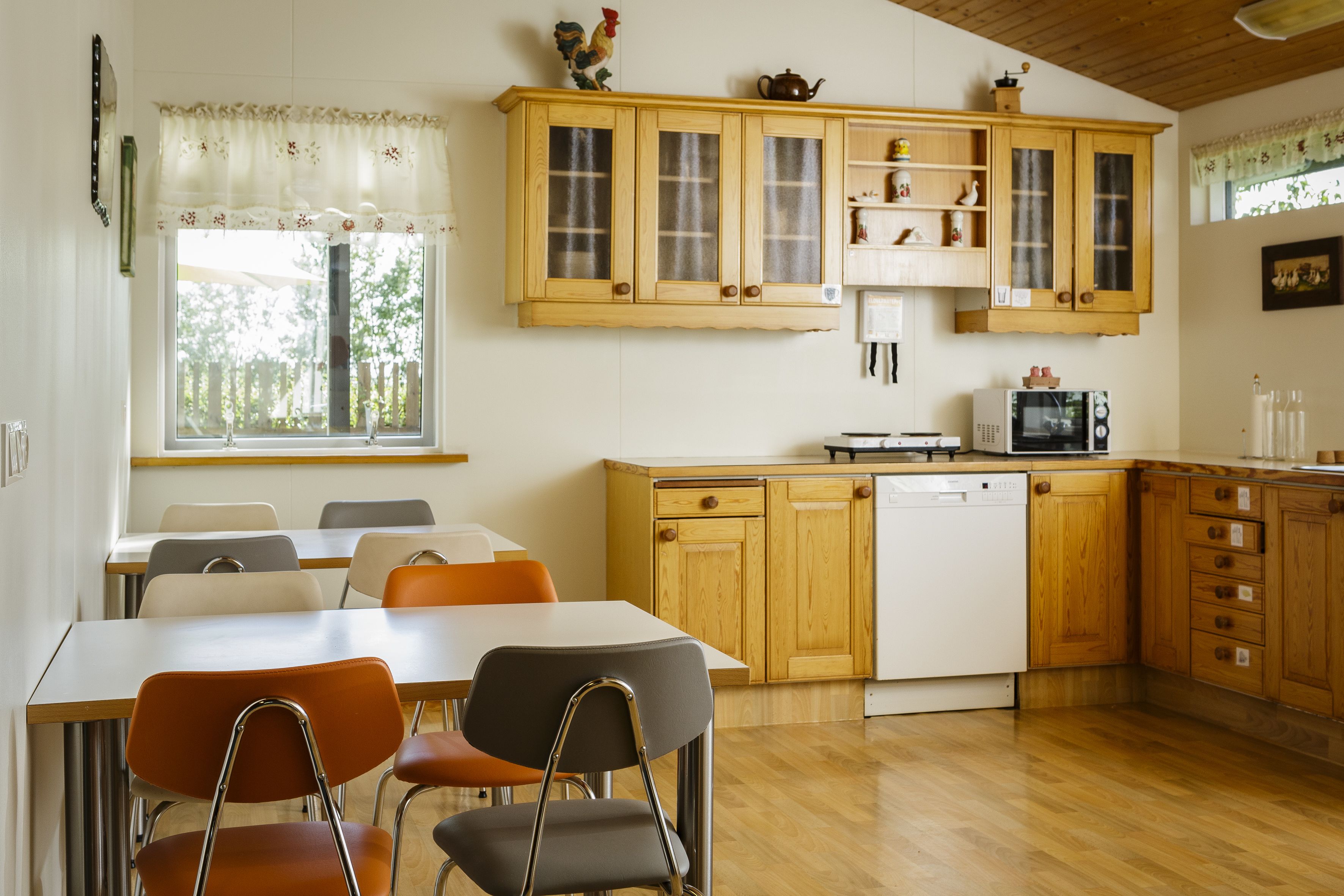 Una cucina con mobili in legno, una lavastoviglie e un forno a microonde. Nell'area pranzo ci sono sedie e un tavolo.