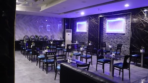 A modern restaurant with marble walls, black and white decor, and blue upholstered chairs. - GSS Avenue Hotel (Dubai)