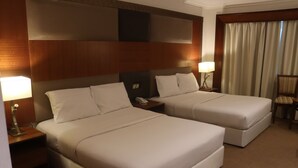 A hotel room with two beds, a nightstand with a lamp, a chair, and a window with curtains. - GSS Avenue Hotel (Dubai)