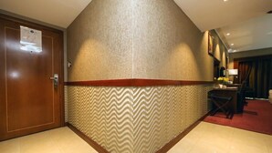 A hotel lobby with a wooden reception desk, a wall with a zigzag pattern, and a door with a notice. - GSS Avenue Hotel (Dubai)