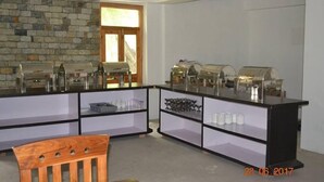 Uma mesa de pequeno-almoço com vários distribuidores de café e uma área de estar com uma cadeira de madeira.