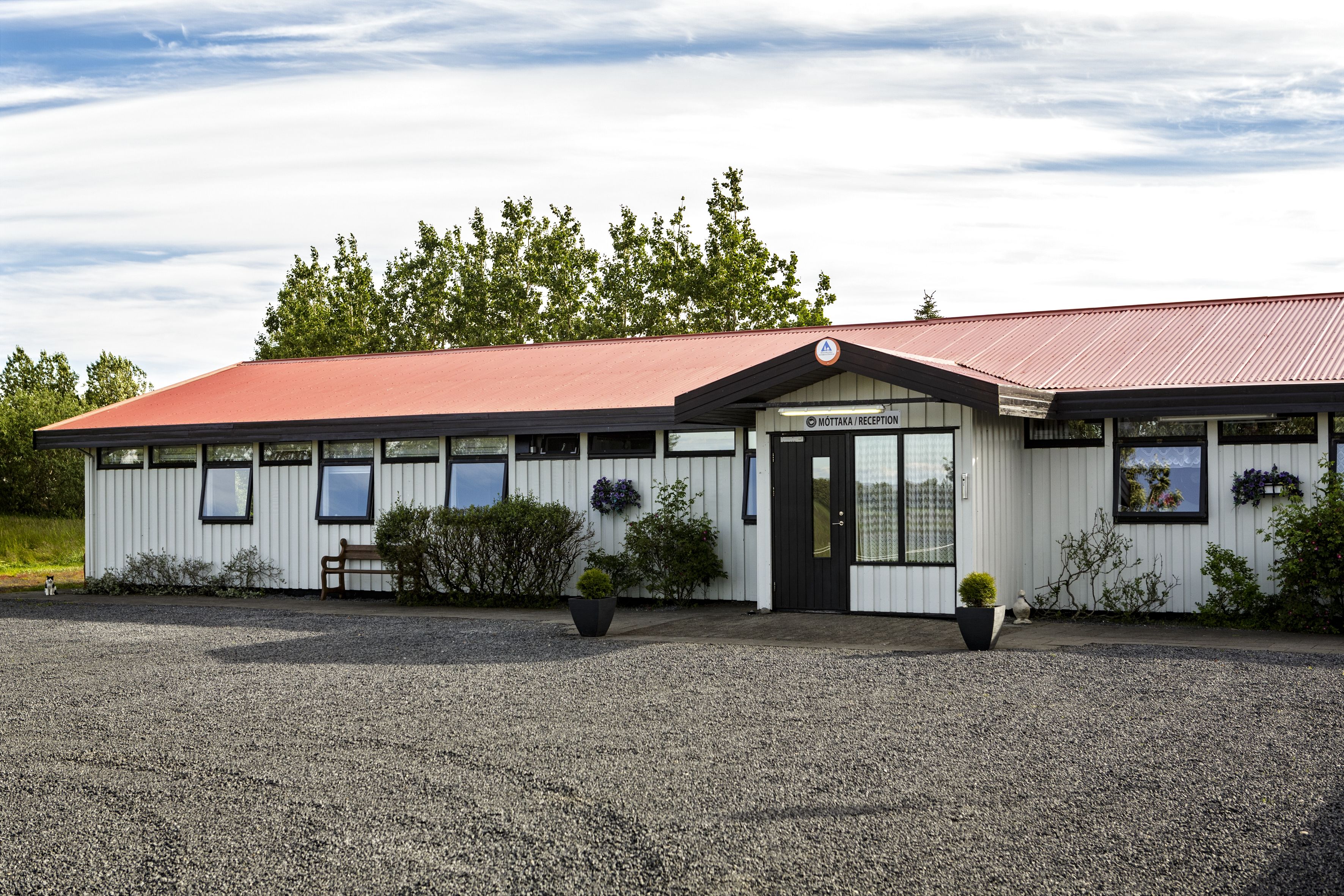 A building with a red roof and white exterior, featuring a reception area with a sign.