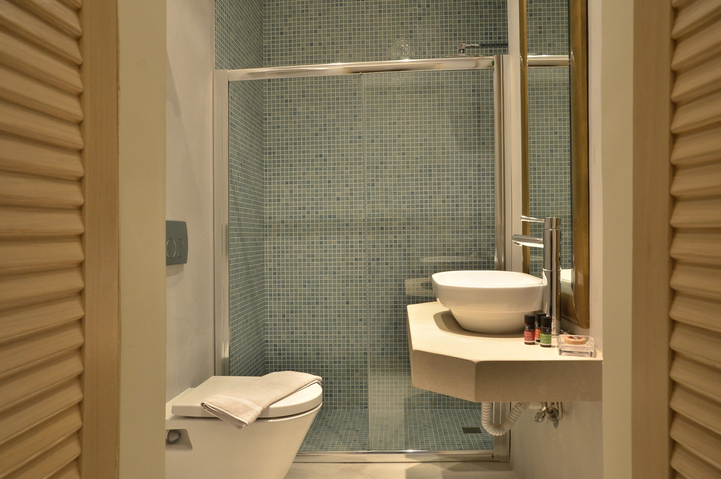 A bathroom with a glass-enclosed shower, a toilet, and a sink with a mirror.