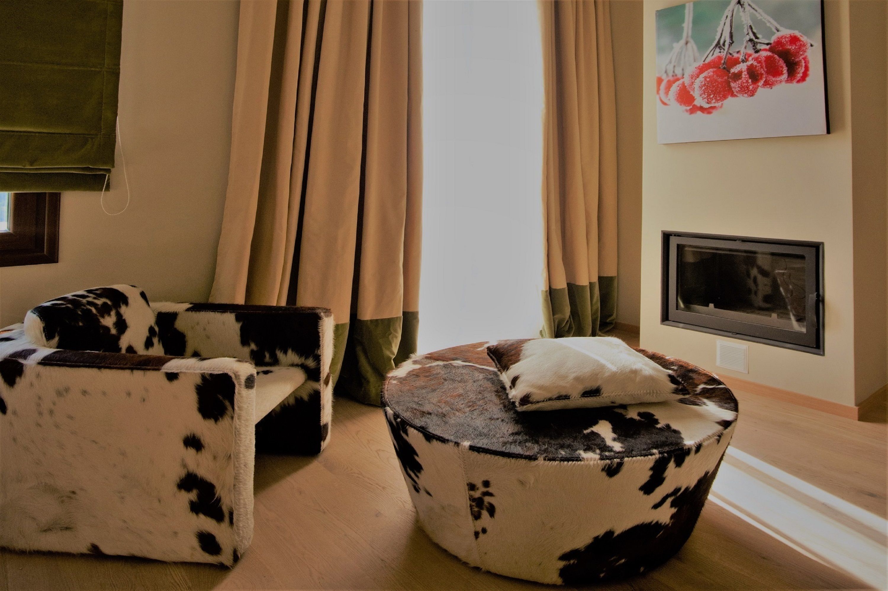 Una habitación con sofá, reposapiés, chimenea y un cuadro en la pared.