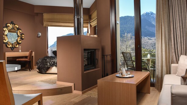 Een moderne woonkamer met een open haard, een eethoek en een balkon met uitzicht op de bergen.