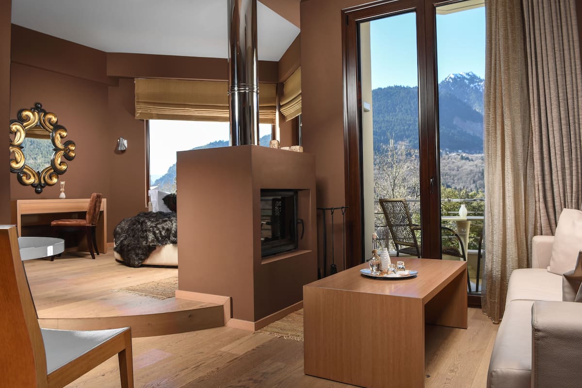 Un salon moderne doté d’une cheminée, d’un coin repas et d’un balcon offrant une vue sur les montagnes.