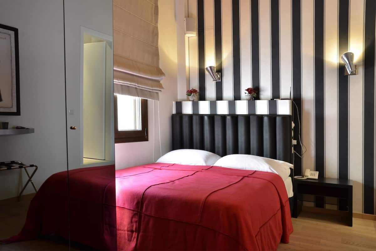 Une chambre d’hôtel équipée d’un lit, d’une table de chevet et d’un luminaire fixé au mur.