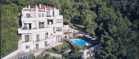 A multi-story building with balconies, a swimming pool, and a mountainous backdrop.