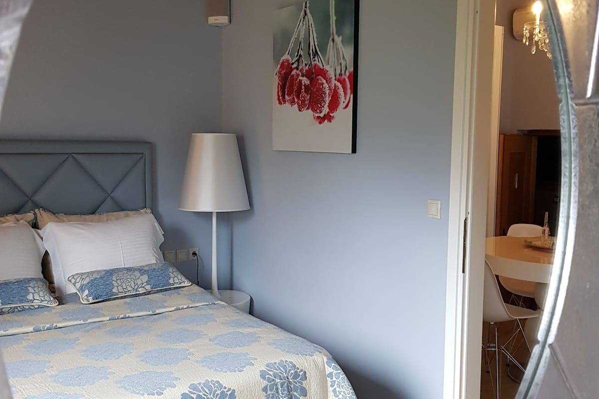 Une chambre à coucher avec un lit, une lampe et un tableau au mur.