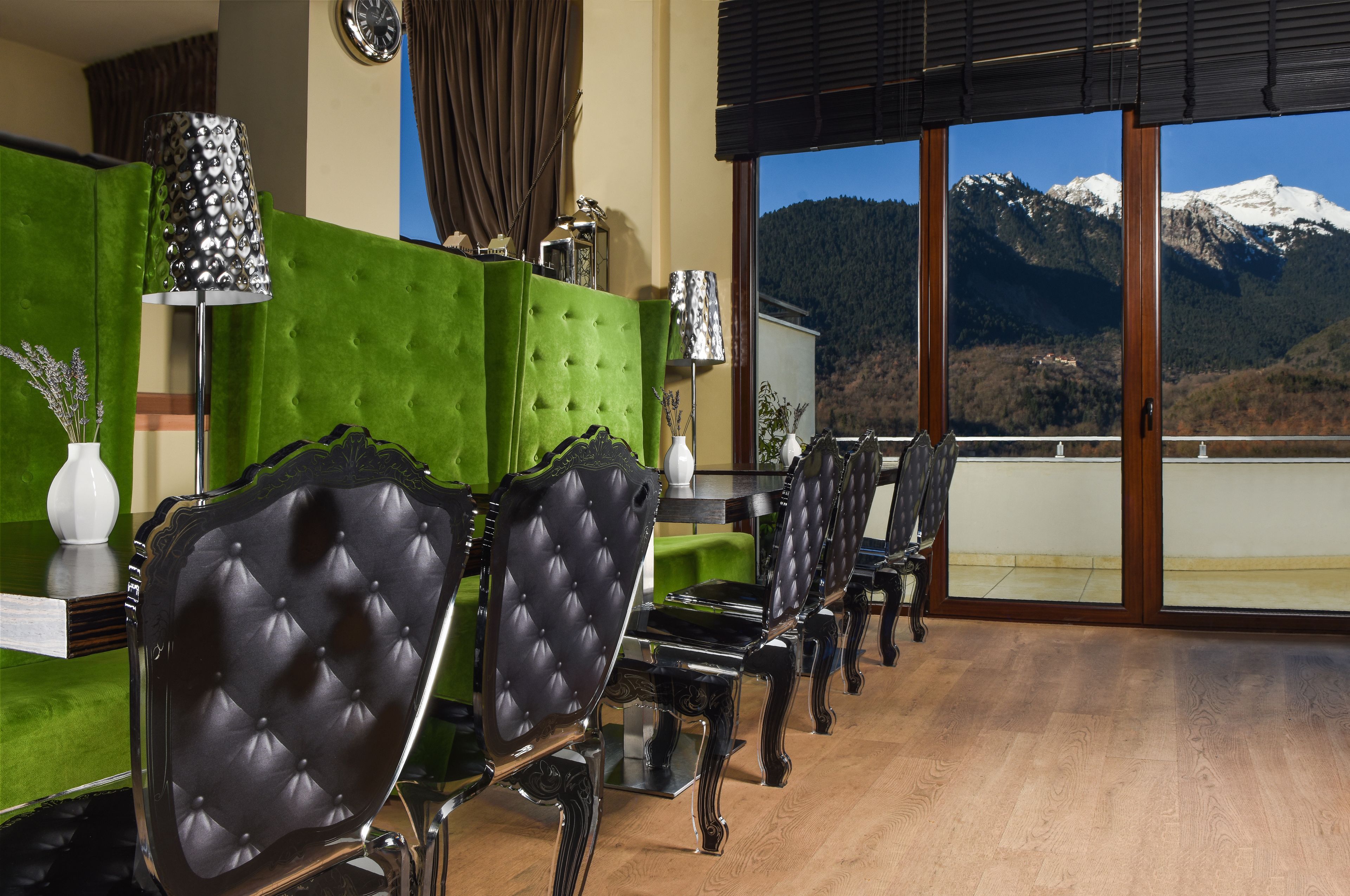 A dining area with a green partition, black upholstered chairs, and a table with a vase and a lamp.