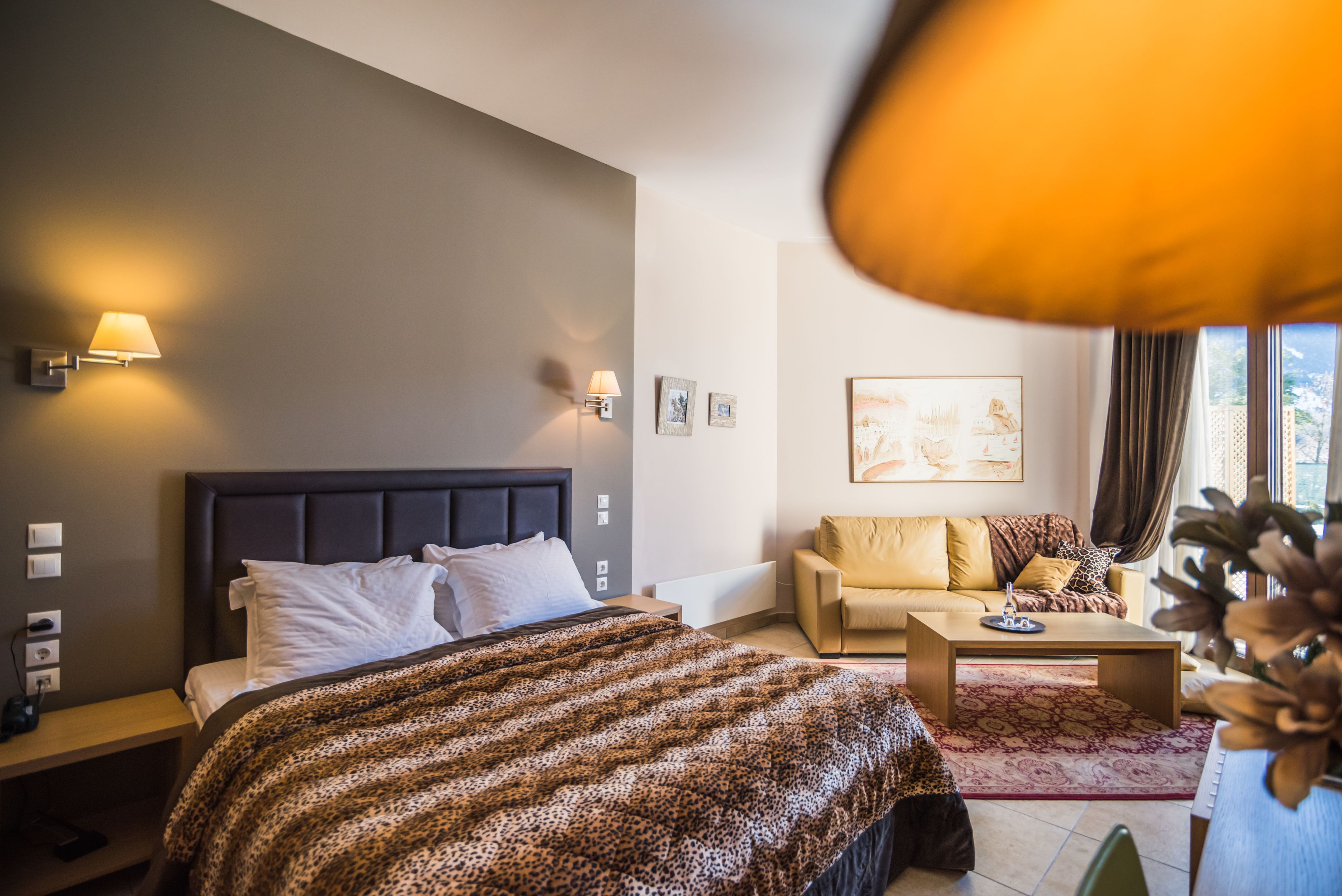 A modern bedroom with a large bed, bedside lamps, a sofa, and a coffee table.