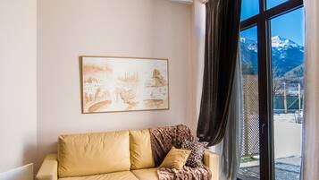 A living room with a sofa, a coffee table, and a large window with a mountain view.