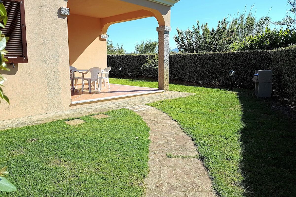 A patio area with a covered seating space, a stone pathway, and a well-maintained lawn.