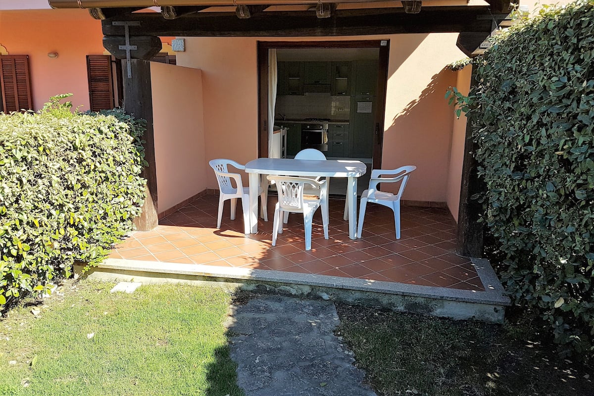 A patio with a table and chairs, a tiled floor, and a building entrance.