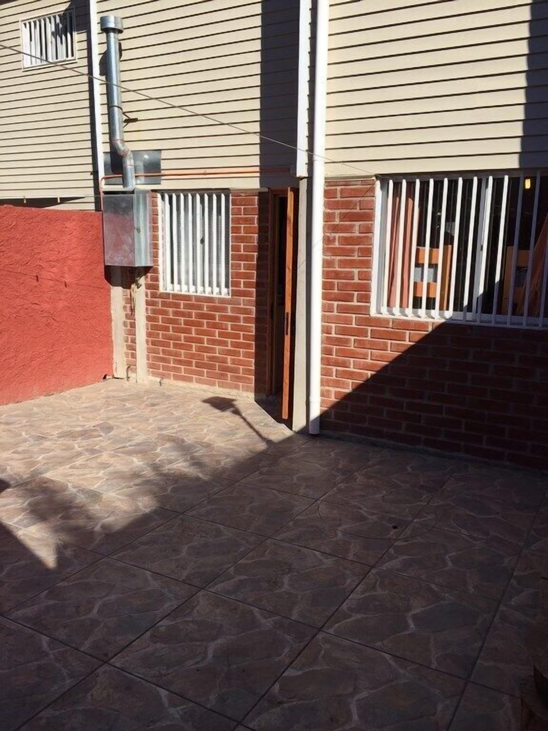 A patio area with stone tiles, a brick wall, and a metal gate.