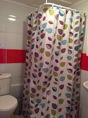 Une salle de bain avec un rideau de douche orné d’un motif de feuilles.